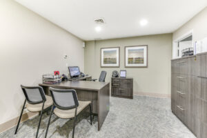 Interior Leasing Office, light brown patterned carpeting, grayish brown furniture, landscape paintings on the walls.