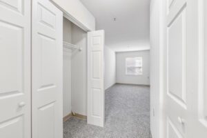 Interior Unit closet, neutral toned carpeting, white walls, accordion doored closet.