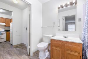 Interior Unit Bathroom, vanity mirror, wood floors, light brown cabinet, white countertop, door to fouyer.