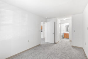 Interior Unit Bedroom, neutral toned carpeting, white walls, attached bathroom and closet, doorway to living room.